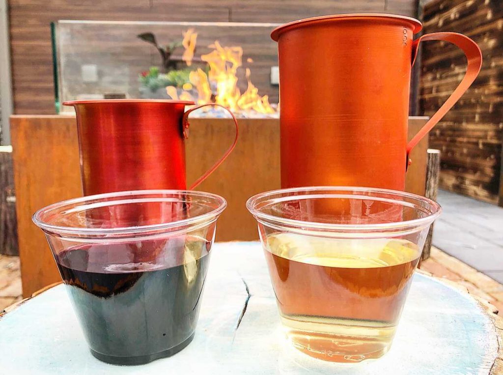two plastic cups of wine, one red and one white